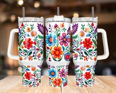 three colorful floral tumblers sitting on top of a wooden table