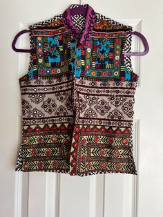 a colorful vest hanging on a door with a purple ribbon around the neck and two pockets at the waist