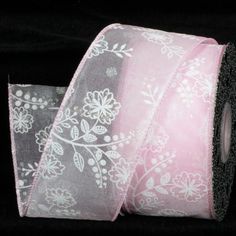 two rolls of pink and black ribbon with white floral designs on the side, against a black background