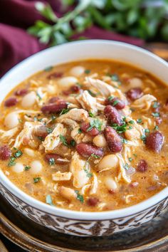 a close up of a bowl of soup with beans and meat in it on a plate