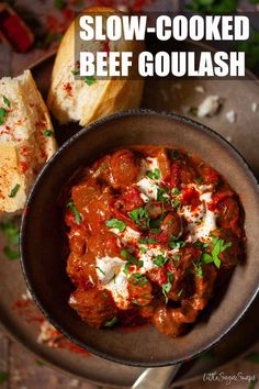 slow cooked beef goulash in a skillet with bread and parsley on the side