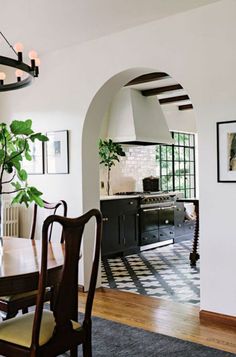 an arched doorway leads into a kitchen with black and white tile