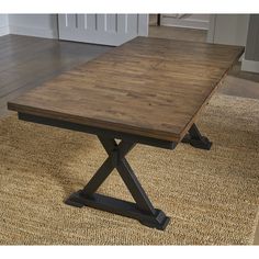 a wooden table sitting on top of a rug in front of a white door way