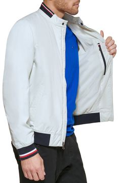 Subtle logo detailing adds signature touches throughout this lightweight bomber jacket with dual front-slant pockets and ribbed banding at the collar and cuffs. 28 1/2" length Stand collar with snap-tab closure Lined 90% polyester, 10% spandex Machine wash, tumble dry Imported Casual Track Jacket With Elastic Cuffs For Spring, Casual Spring Track Jacket With Elastic Cuffs, Fitted Casual Tommy Hilfiger Outerwear, Casual Nylon Outerwear With Elastic Cuffs, Casual White Outerwear With Elastic Cuffs, Spring Urban Track Jacket With Ribbed Cuffs, Casual Windbreaker With Ribbed Cuffs For Work, Casual Nylon Track Jacket With Padded Collar, White Outerwear With Ribbed Collar For Spring