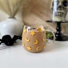 a coffee mug with yellow stars and moon designs on it sitting on a white table