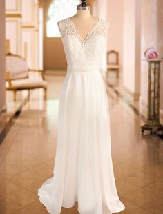 a white wedding dress on display in a room with beige walls and tile flooring