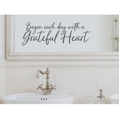 a bathroom with two sinks and a large framed sign above it that says, begin each day with a grateful heart