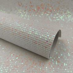 a roll of white glitter paper on top of a tablecloth covered in confetti