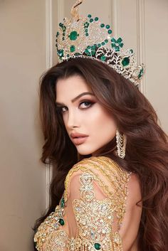 a beautiful woman wearing a tiara and posing for the camera with her hair blowing in the wind