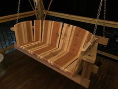 a wooden swing with chains hanging from it's sides on a deck at night