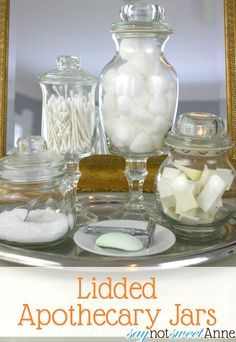 an assortment of glass jars filled with white sugar and marshmallows in front of a gold framed mirror