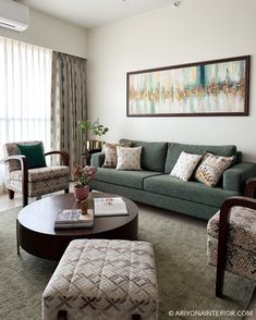 a living room filled with furniture and a painting hanging on the wall above it's windows