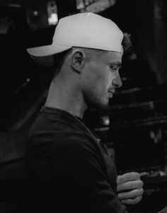 black and white photograph of a man wearing a baseball cap looking at his cell phone