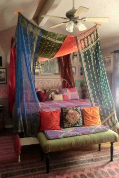 a canopy bed with lots of colorful pillows on top of it and a rug in front of it