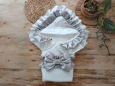 a white shirt with grey ruffles and a bow tie on the collar is sitting on a wooden table