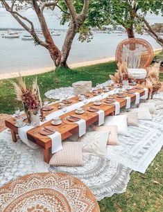 a table set up with plates and place settings for an outdoor dinner by the water