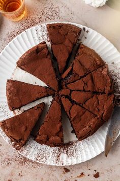 a chocolate cake on a paper plate with powdered sugar around the edges and one slice missing