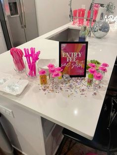 a white counter topped with lots of pink decorations and confetti on top of it