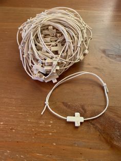 a string of white cords and a cross on top of a wooden table