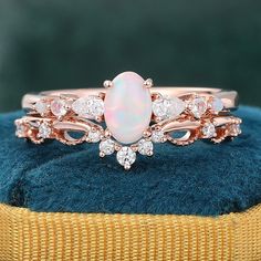 an opal and diamond ring sits on top of a blue velvet cushion