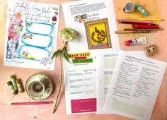 the contents of a crafting kit laid out on a wooden table with markers, pens and paper