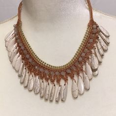 a necklace with white stones and beads on a mannequin