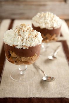 two desserts sitting on top of a table with spoons