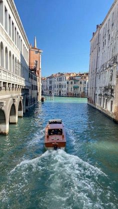 a boat traveling down a river next to tall buildings and water bridges in venice, italy