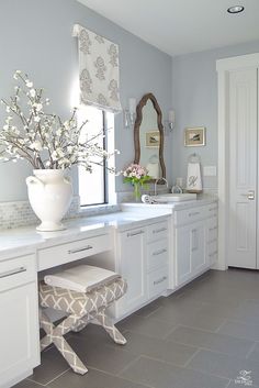 a bathroom with white cabinets and gray tile flooring is decorated in shades of blue