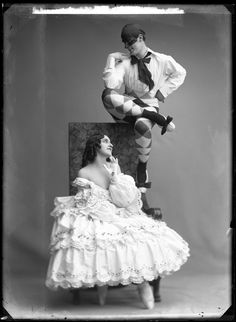 an old photo of a man and woman dressed as clowns sitting on a chair