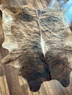 a cowhide rug is laying on the floor in front of a wooden flooring