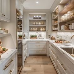 a kitchen filled with lots of white cabinets and counter top space next to a wooden floor