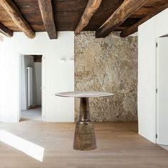 a round table sitting in the middle of a room with exposed wood beams on the ceiling