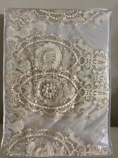 an intricately designed pillow with white lace on the front and back, sitting on a table