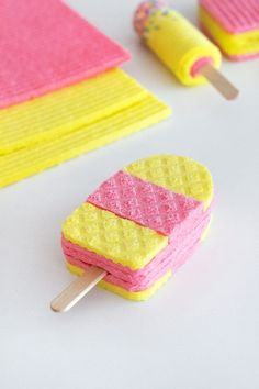 two popsicles with yellow and pink frosting on them, next to each other