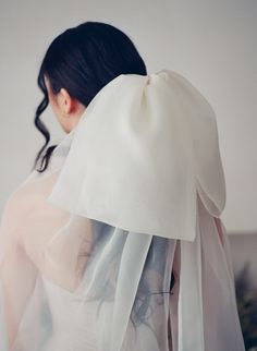 a woman wearing a white veil with her hair pulled back and looking down at the ground