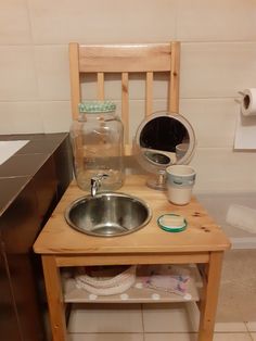 a small wooden table with a sink and some jars on it in a bathroom stall