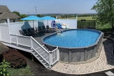 an above ground swimming pool with steps leading up to the deck and umbrellas over it