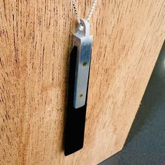 a knife is hanging from the side of a wooden door with a chain on it