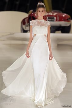 a model walks down the runway in a white gown with sheer shoulders and an open back