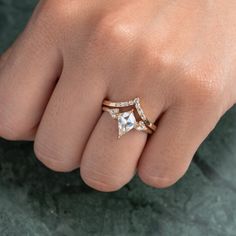 a person's hand with two rings on their fingers and one has an engagement ring