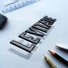 a pencil and some type of lettering on paper