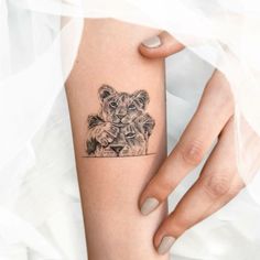 a woman's arm with a small tattoo on it, depicting two lions holding each other