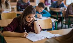 there are many students sitting at desks in the classroom and one student is taking notes