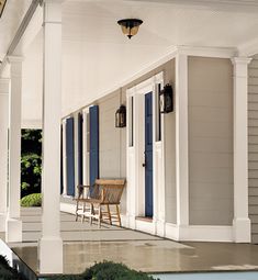 the front porch of a house with blue shutters and two chairs on either side