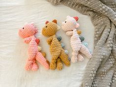 three crocheted teddy bears laying on top of a white blanket next to each other