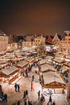 an aerial view of a christmas market with people walking around and trees in the background