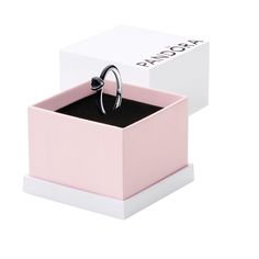 a ring sits in a pink box with a black diamond on the top and bottom