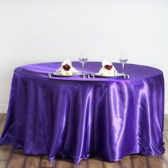 two wine glasses are sitting on top of a purple table cloth