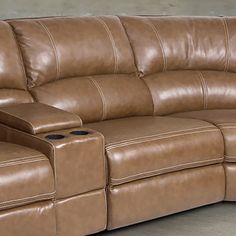 a brown leather couch sitting on top of a floor next to a tv remote control